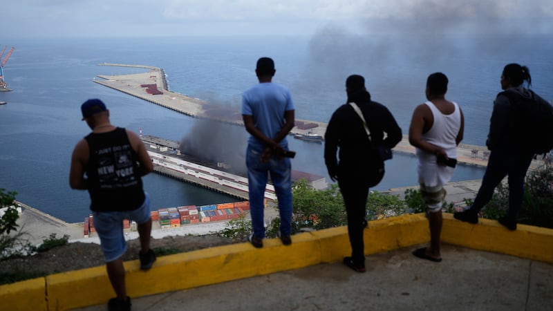 Varios hombres observan el humo que se levanta en un muelle tras las explosiones que se...