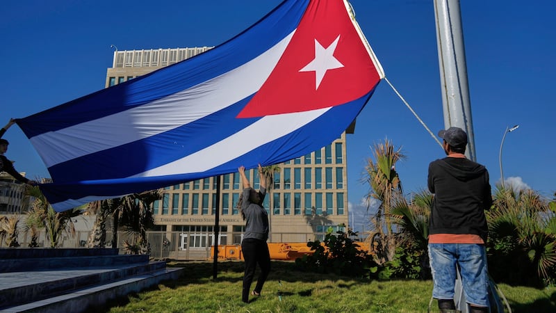Trabajadores colocan la bandera cubana a media asta en la Tribuna Antiimperialista, cerca de...