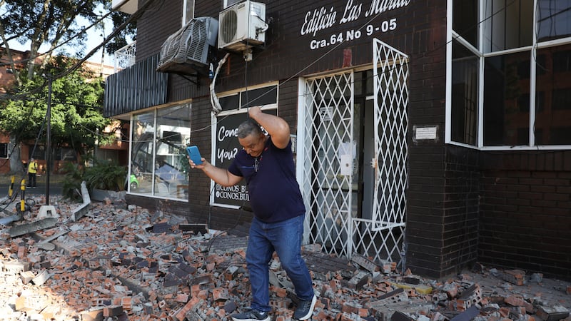 A man leaves an apartment building after an earthquake struck Cali, Colombia, Monday, Aug. 10,...