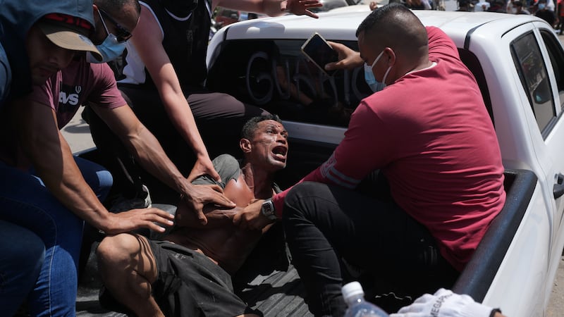Residents transport a man rescued from the rubble three days after earthquakes struck, in La...