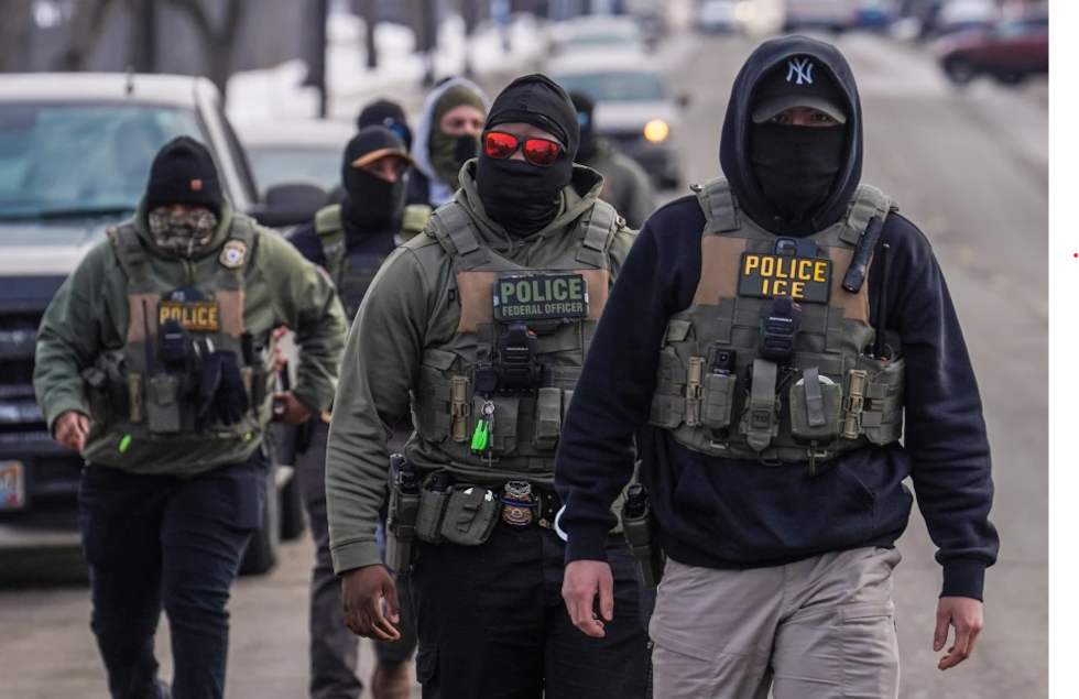 Federal agents walk down a street while conducting immigration enforcement operations in...