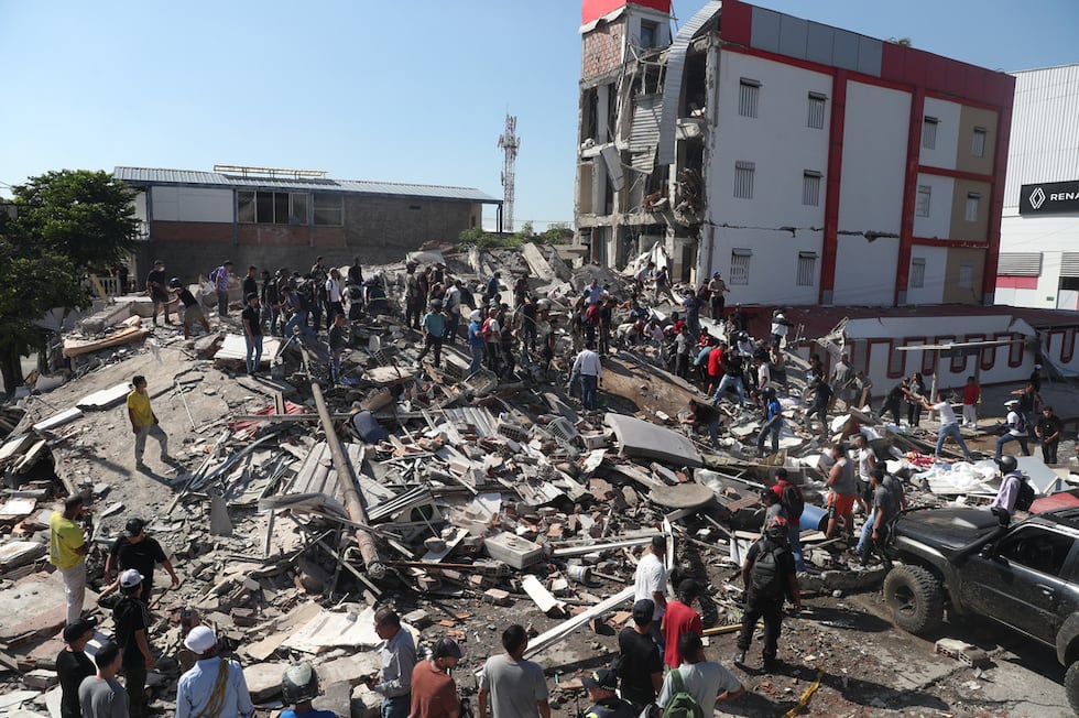 Residentes y equipos de rescate buscan entre los escombros de un edificio derrumbado tras el...