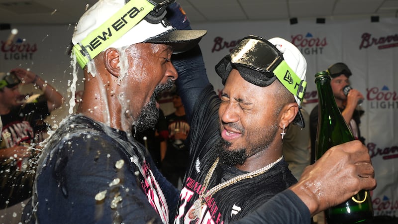 Ozzie Albies, derecha, de los Bravos de Atlanta, celebra en la casa club del equipo visitante...