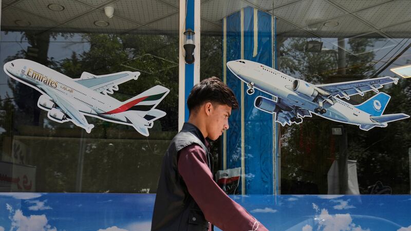 An Afghan man passes in front of an air travel agency in Kabul, Afghanistan, Thursday, June 5,...