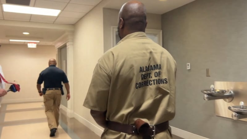 Jeremy Williams walks through a hallway escorted by an Alabama Department of Corrections...