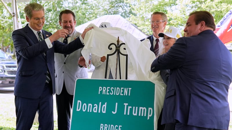 Treasury Secretary Scott Bessent, left, unveils a sign during a ceremony to rename a bridge...